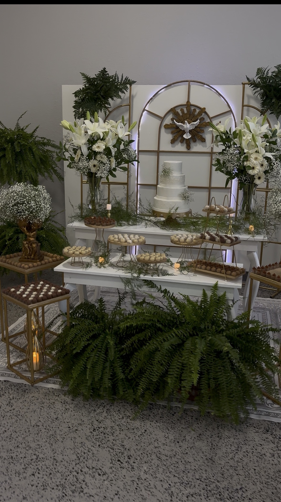 Mesa de doces do Império Reis decorada com bolo, flores brancas e detalhes dourados